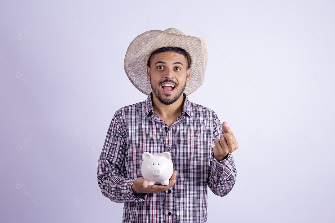 Homem jovem barbudo fantasiado celebrando festas juninas segurando cofrinho