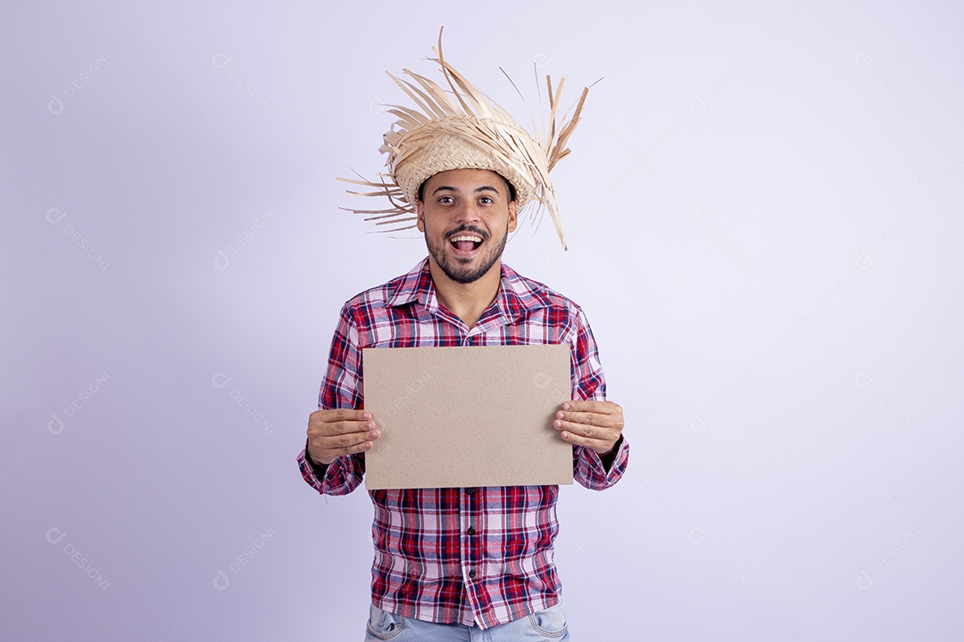 Homem jovem barbudo fantasiado celebrando festas juninas segurando papel