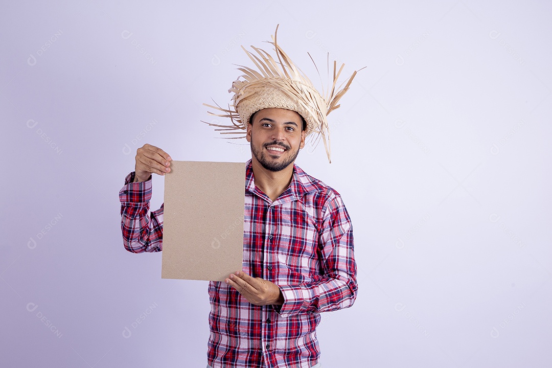 Homem jovem barbudo fantasiado celebrando festas juninas segurando papel