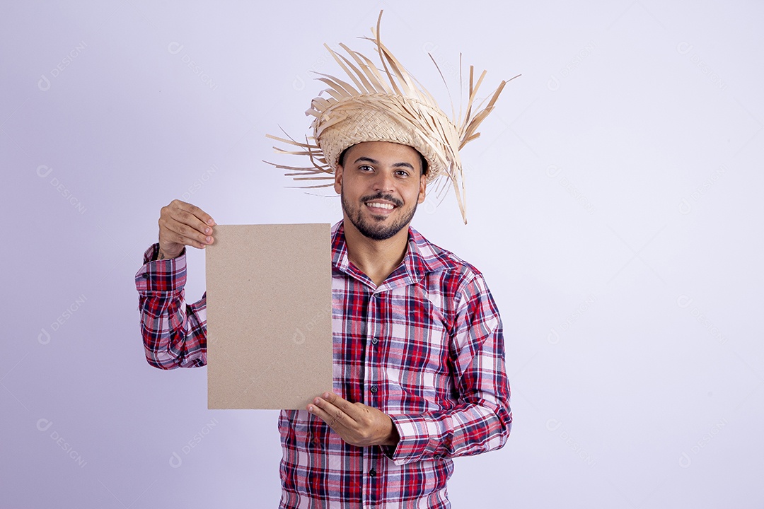 Homem jovem barbudo fantasiado celebrando festas juninas segurando papel