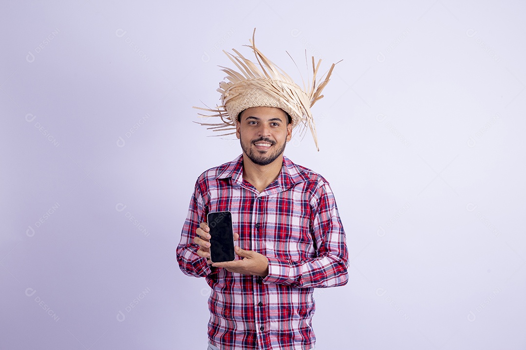 Homem jovem barbudo fantasiado celebrando festas juninas segurando celular