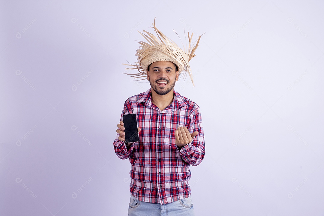Homem jovem barbudo fantasiado celebrando festas juninas segurando celular