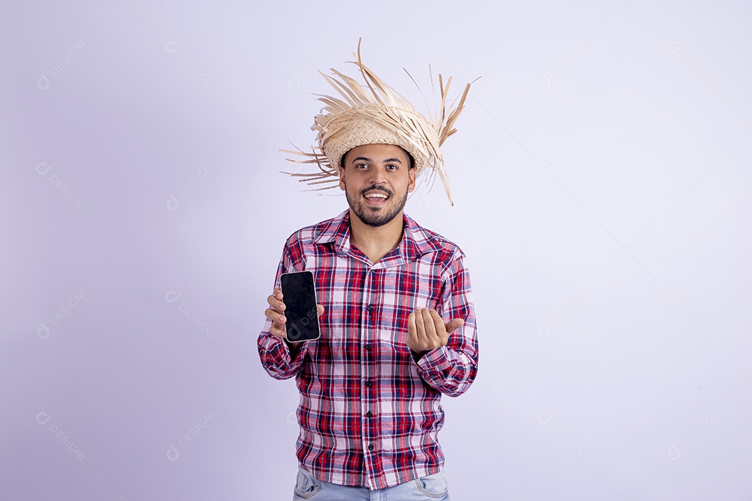 Homem jovem barbudo fantasiado celebrando festas juninas segurando celular