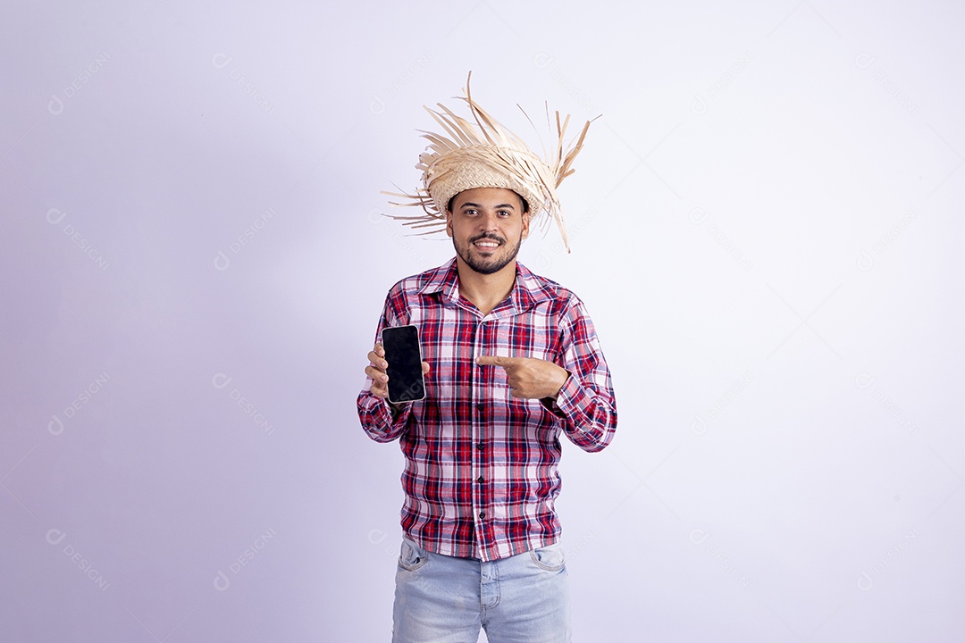 Homem jovem barbudo fantasiado celebrando festas juninas segurando celular