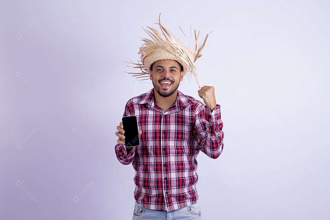 Homem jovem barbudo fantasiado celebrando festas juninas segurando celular