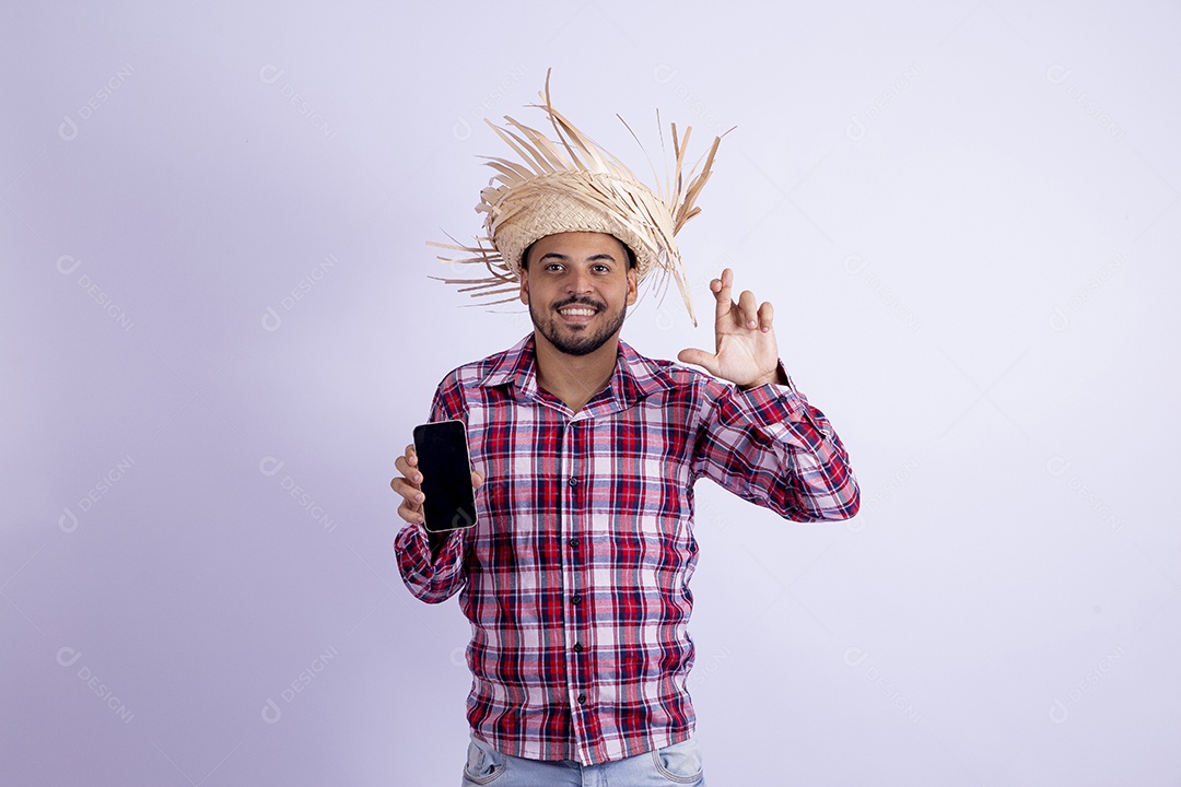 Homem jovem barbudo fantasiado celebrando festas juninas segurando celular