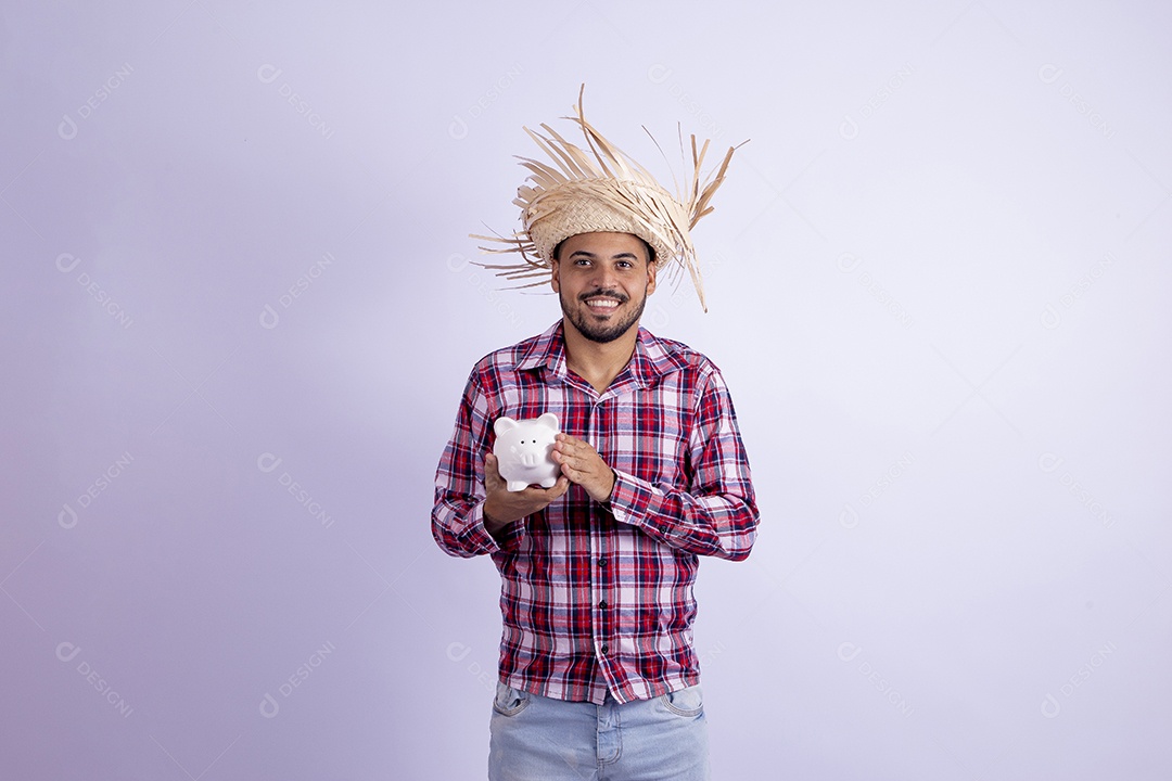 Homem jovem barbudo fantasiado celebrando festas juninas segurando cofrinho
