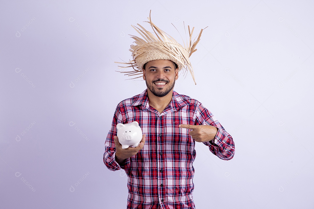 Homem jovem barbudo fantasiado celebrando festas juninas segurando cofrinho