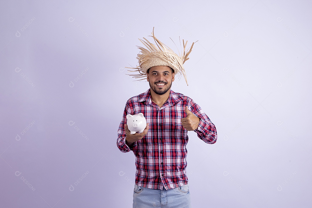 Homem jovem barbudo fantasiado celebrando festas juninas segurando cofrinho