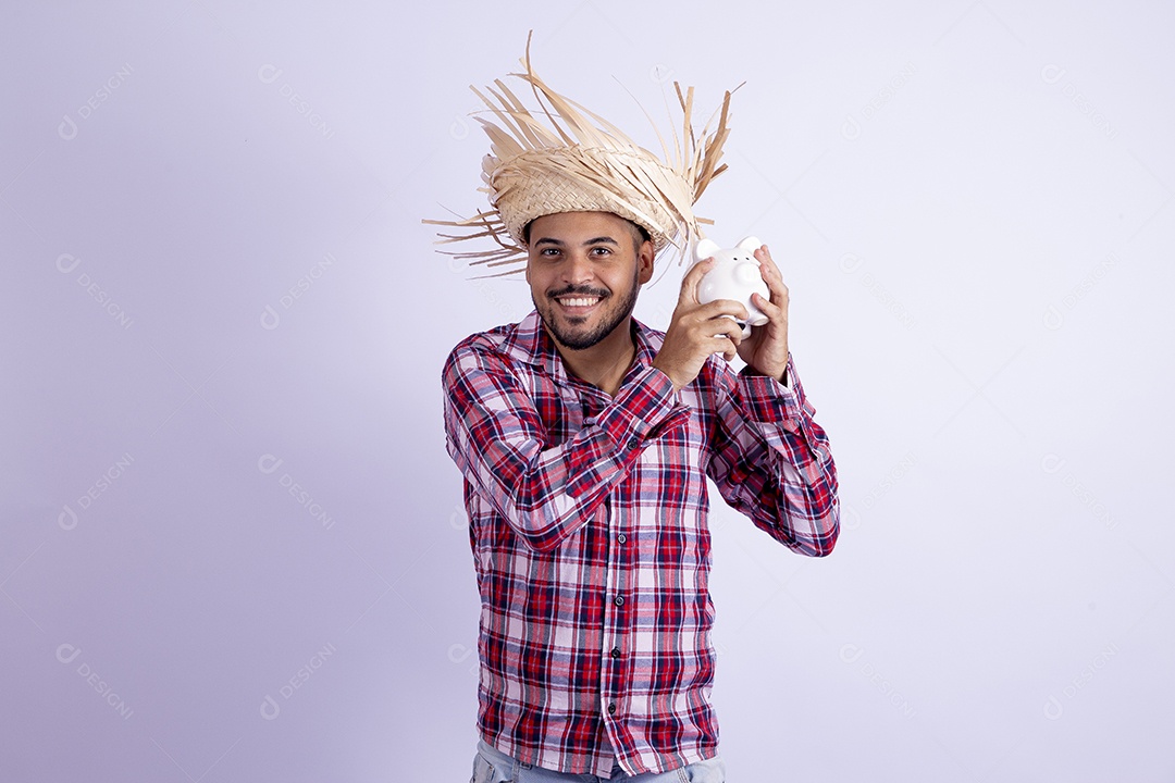 Homem jovem barbudo fantasiado celebrando festas juninas segurando cofrinho