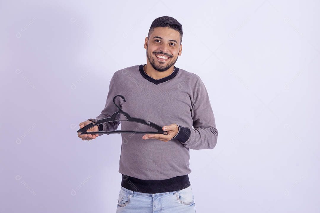 Homem jovem barbudo segurando cabide sobre fundo isolado