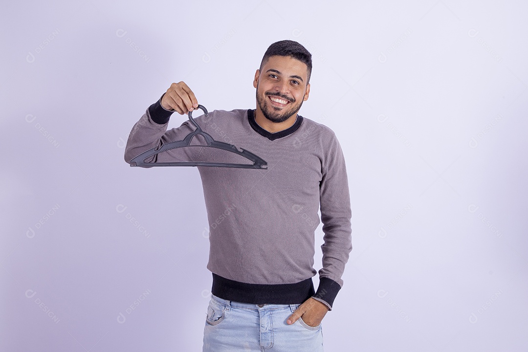 Homem jovem barbudo segurando cabide sobre fundo isolado