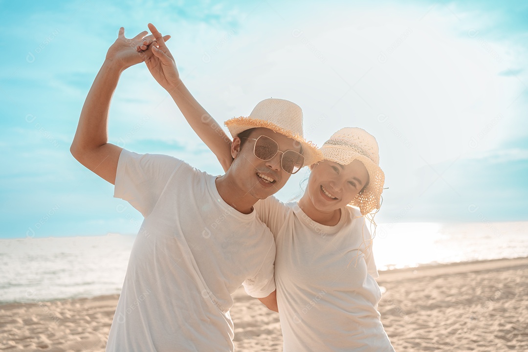 Casal asiático viaja na praia sorrindo liberdade ao pôr do sol no estilo de vida de atividade de fim de semana.