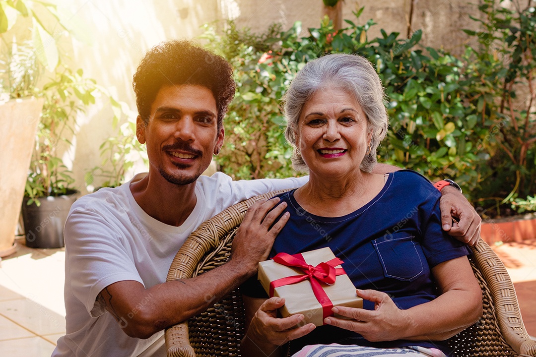 Mãe caucasiana e seu filho negro no jardim da casa. Família inter-racial feliz.
