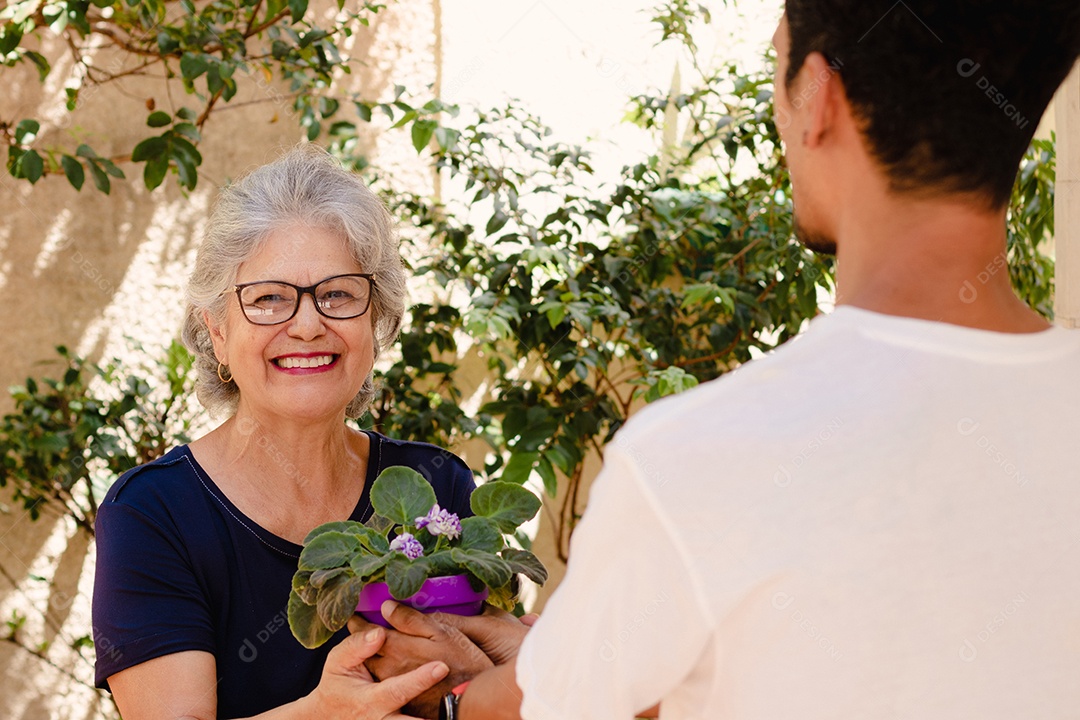 Mãe caucasiana e seu filho negro no jardim da casa. Família inter-racial feliz.