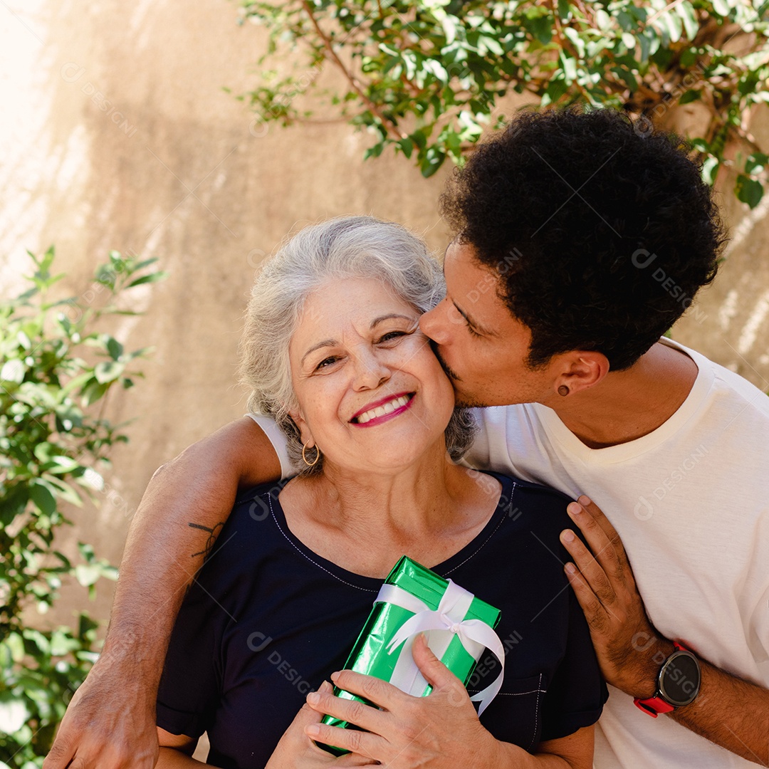 Mãe caucasiana e seu filho negro no jardim da casa. Família inter-racial feliz.