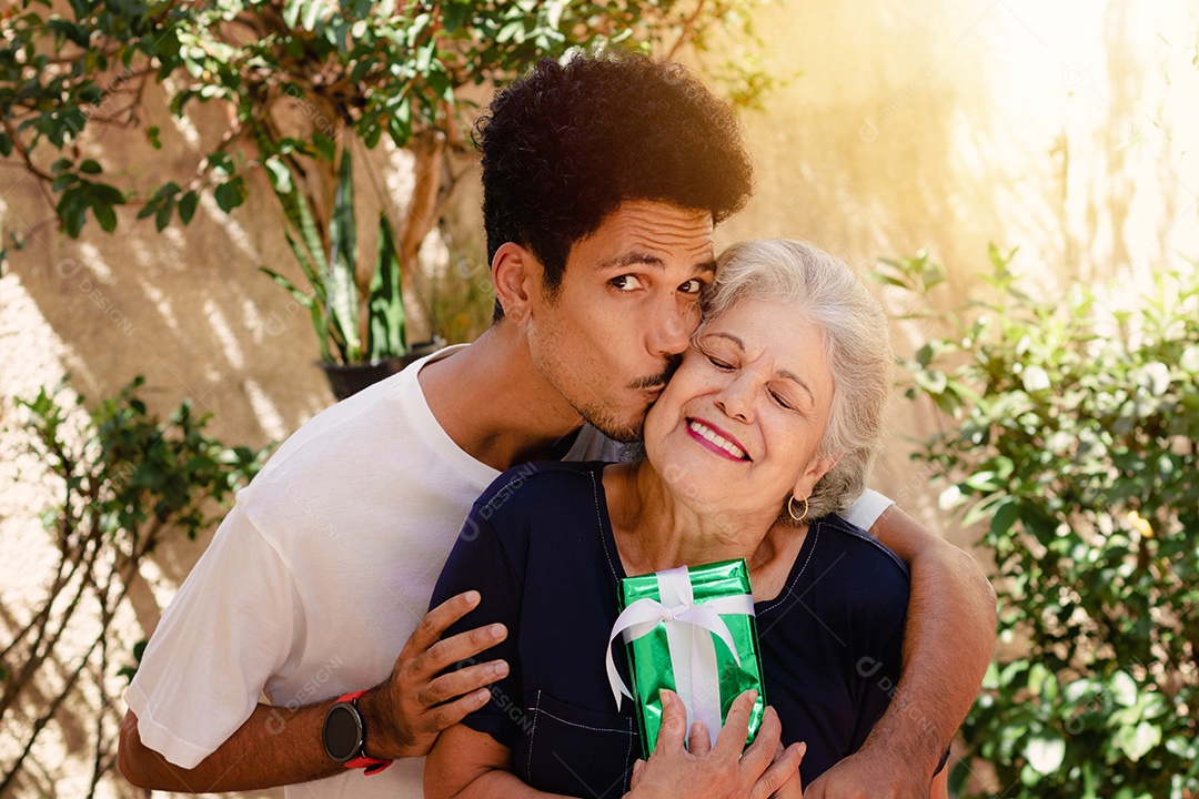 Mãe caucasiana e seu filho negro no jardim da casa. Família inter-racial feliz.