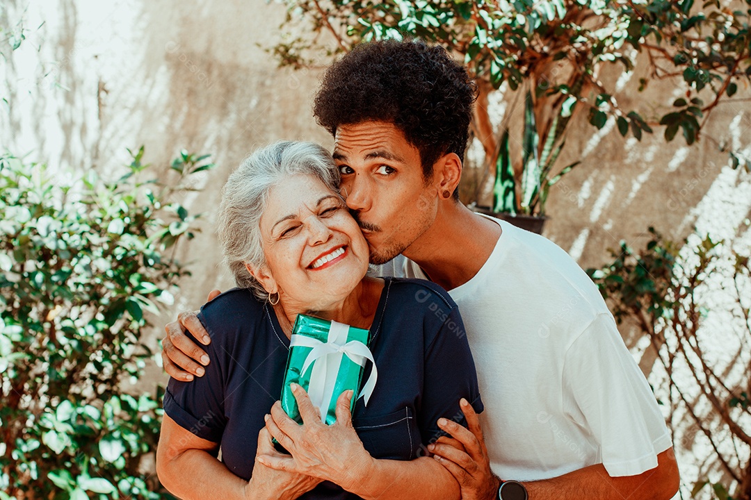 Mãe caucasiana e seu filho negro no jardim da casa. Família inter-racial feliz.