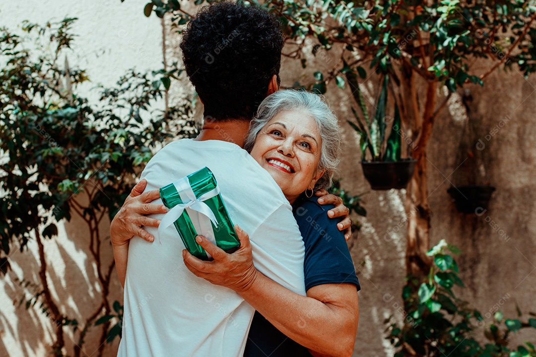 Mãe caucasiana e seu filho negro no jardim da casa. Família inter-racial feliz.