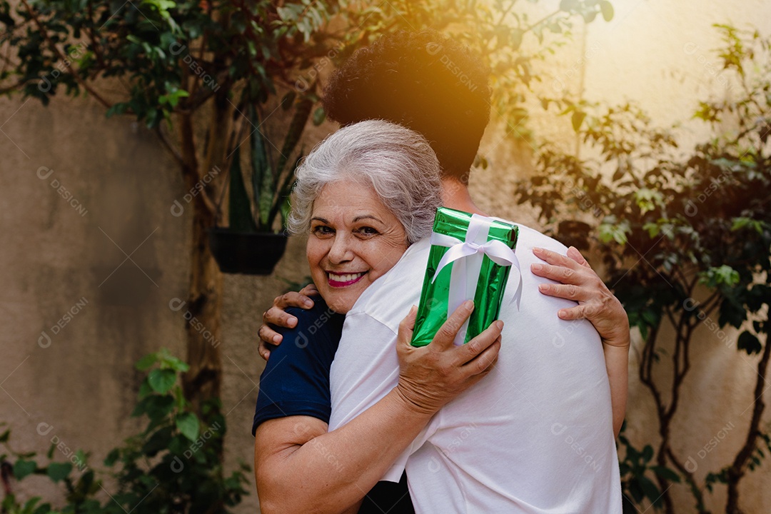 Mãe caucasiana e seu filho negro no jardim da casa. Família inter-racial feliz.