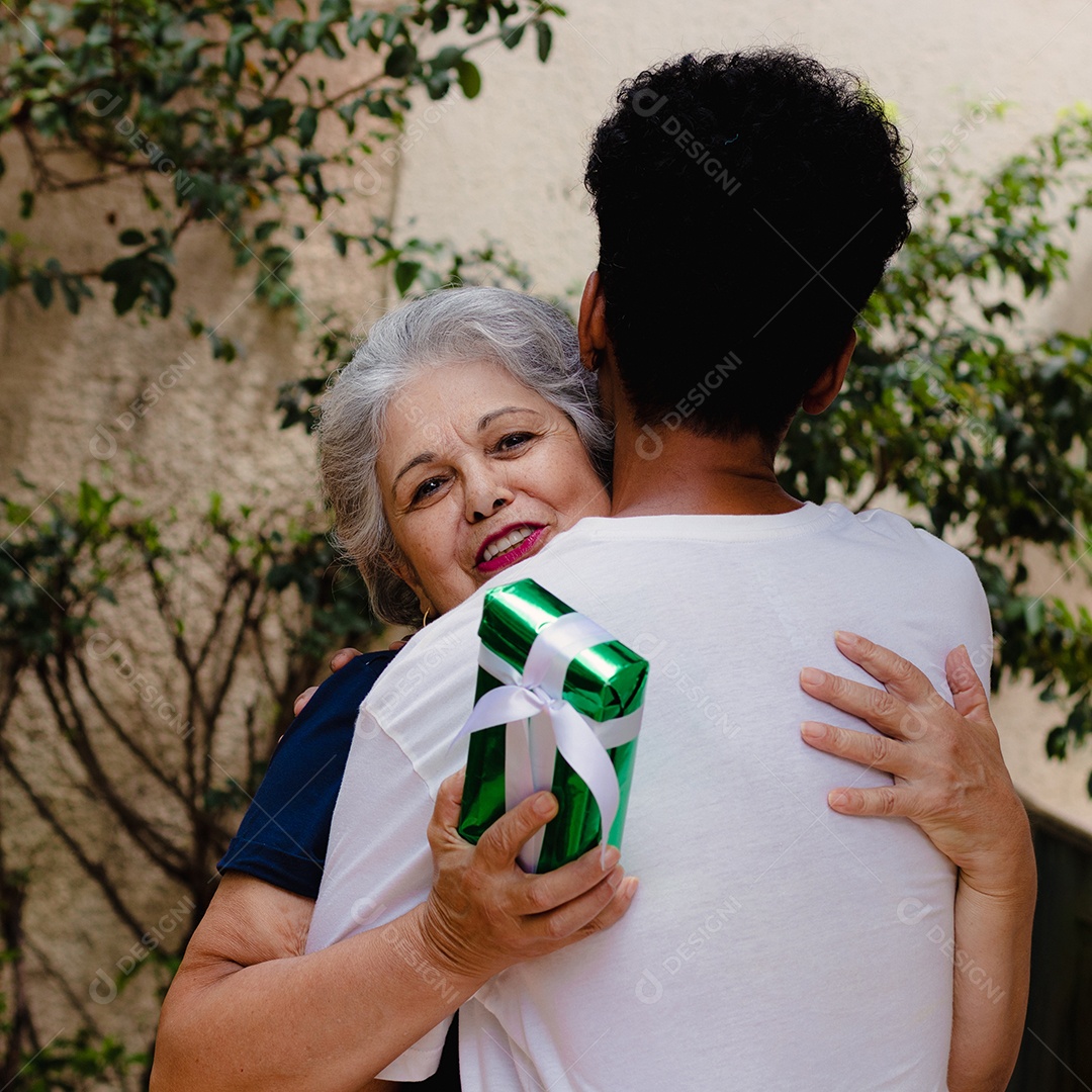 Mãe caucasiana e seu filho negro no jardim da casa. Família inter-racial feliz.