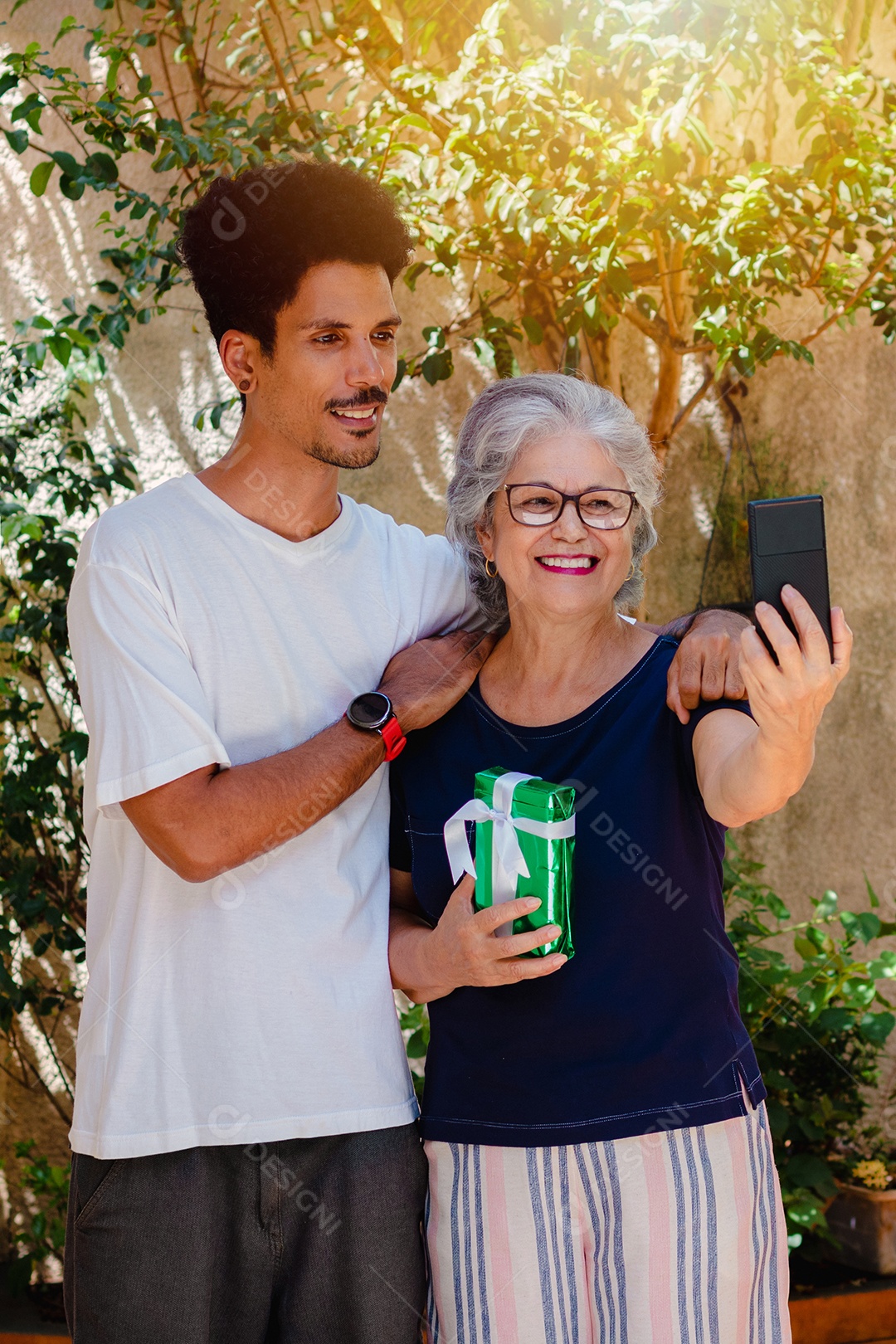 Mãe caucasiana e seu filho negro no jardim da casa. Família inter-racial feliz.