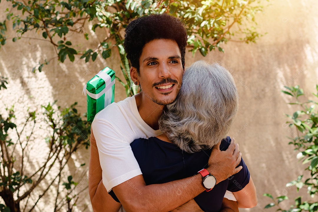 Mãe caucasiana e seu filho negro no jardim da casa. Família inter-racial feliz.