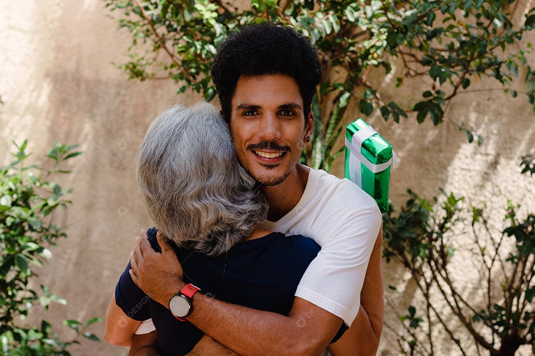 Mãe caucasiana e seu filho negro no jardim da casa. Família inter-racial feliz.