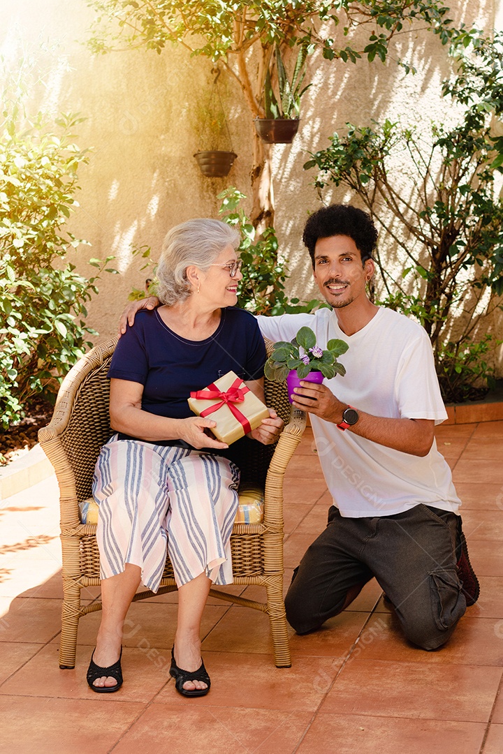 Mãe caucasiana e seu filho negro no jardim da casa. Família inter-racial feliz.