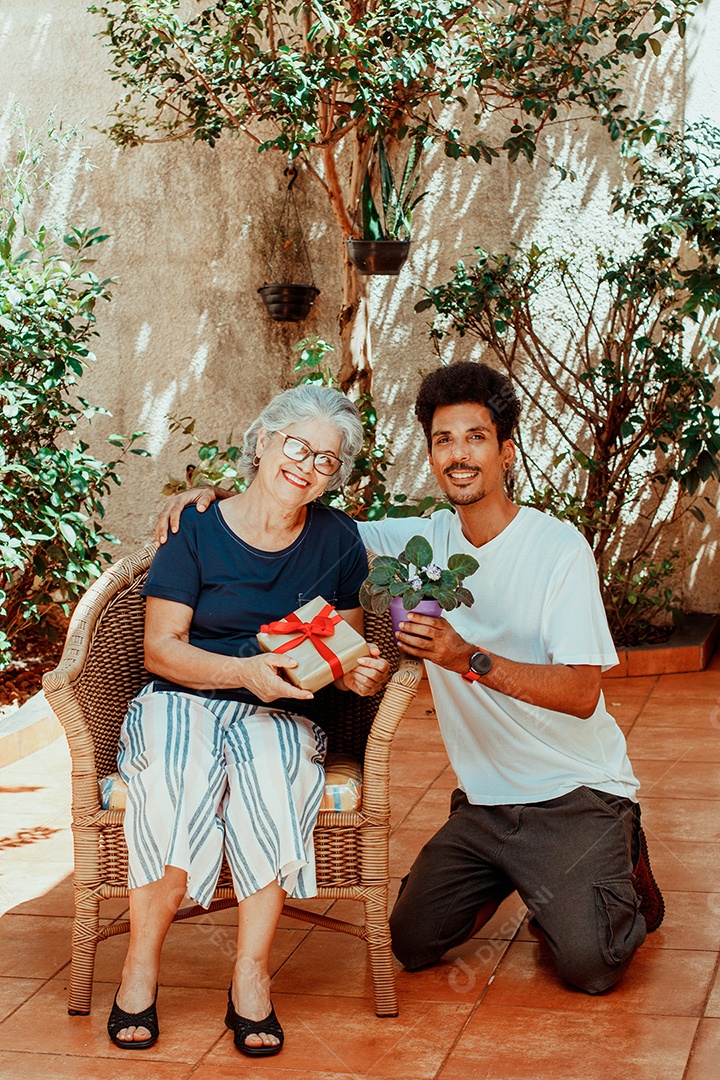 Mãe caucasiana e seu filho negro no jardim da casa. Família inter-racial feliz.
