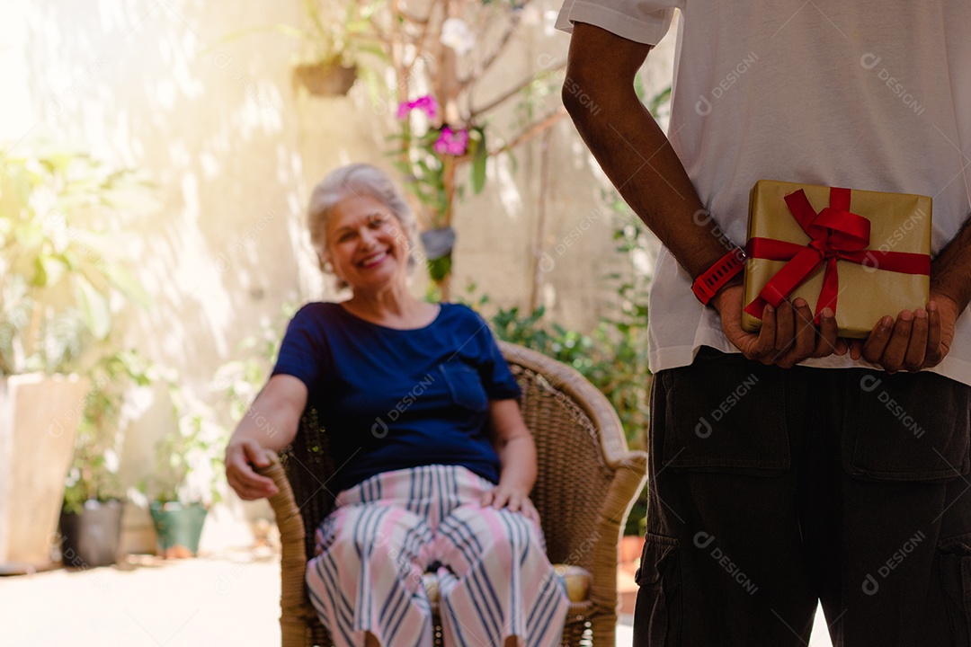 Mãe caucasiana e seu filho negro no jardim da casa. Família inter-racial feliz.