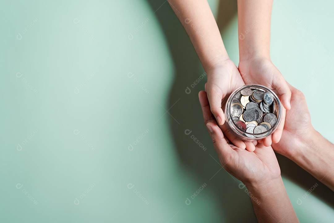 Mãos de adulto e criança segurando pote de dinheiro, doação, poupança