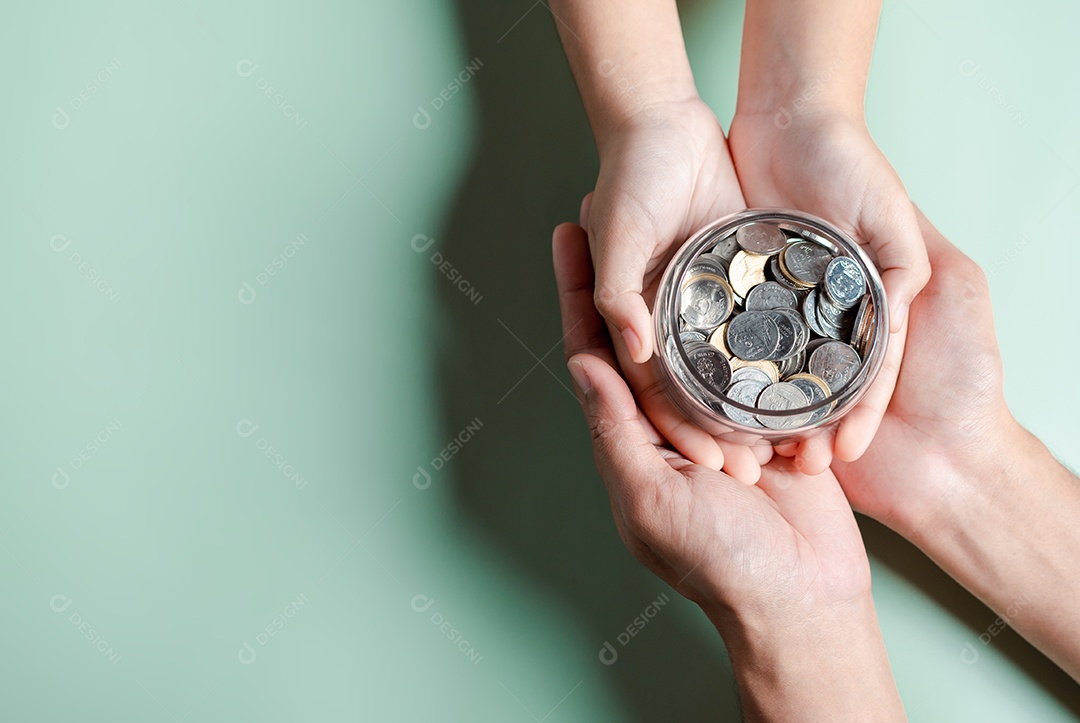 Mãos de adulto e criança segurando pote de dinheiro, doação, poupança