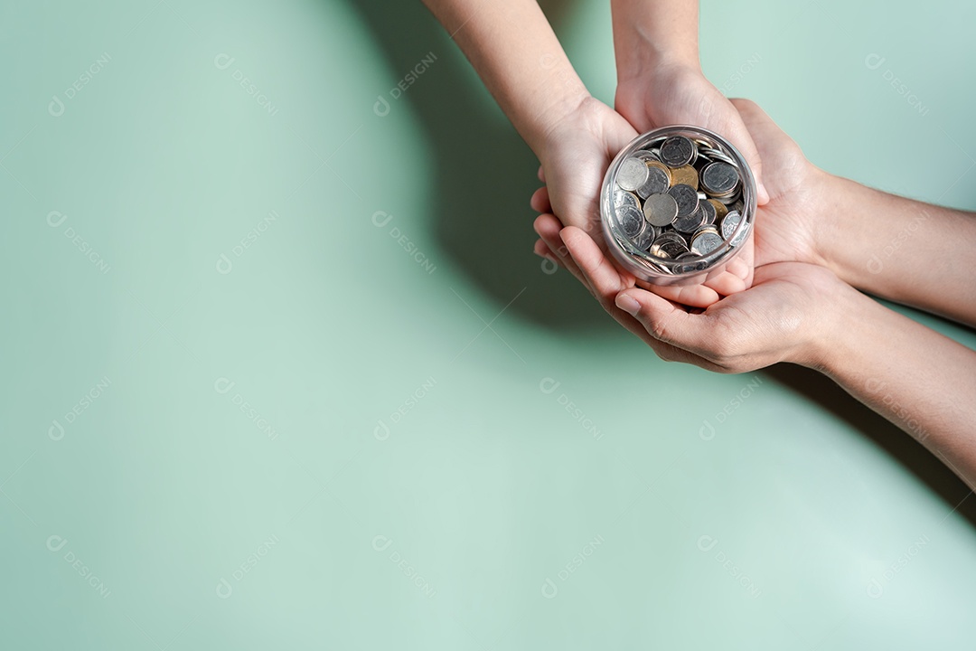 Mãos de adulto e criança segurando pote de dinheiro, doação, poupança