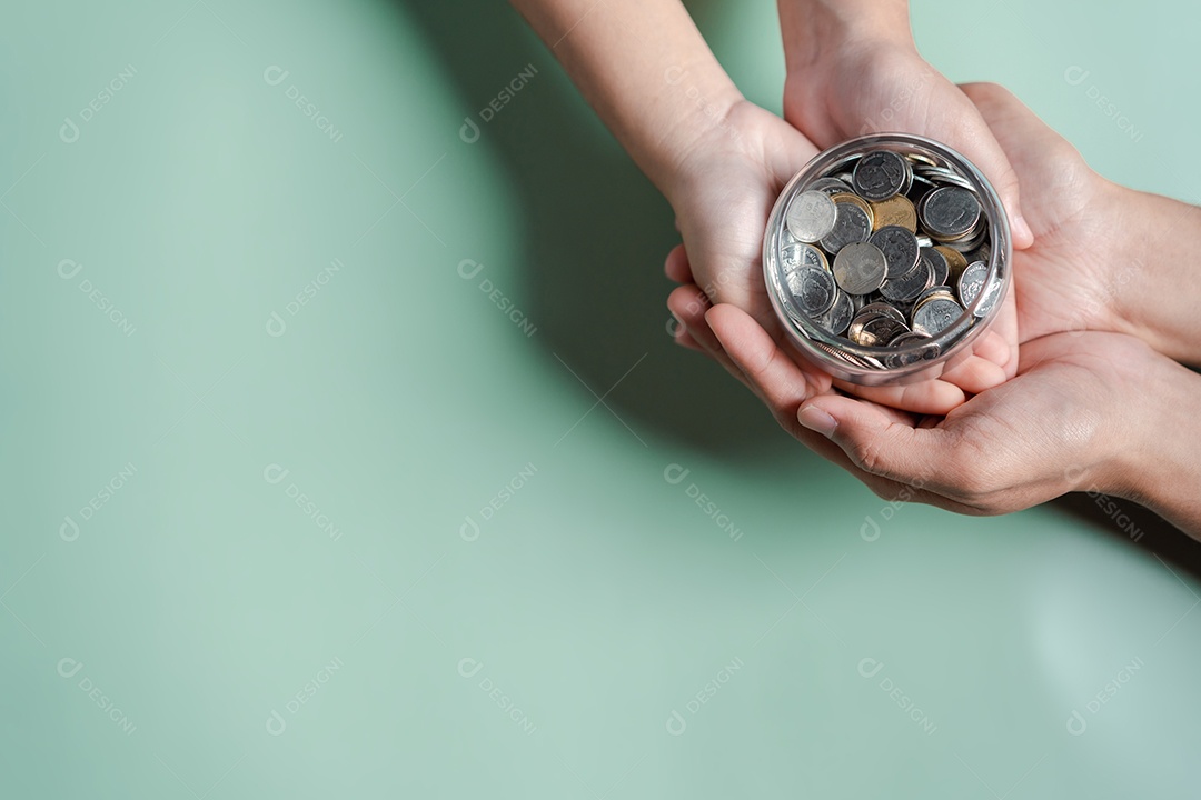 Mãos de adulto e criança segurando pote de dinheiro, doação, poupança