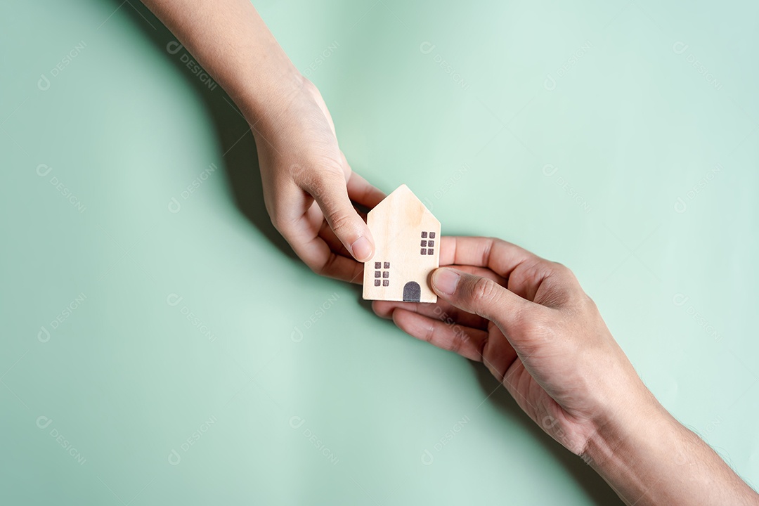 Mãos segurando uma casa de madeira