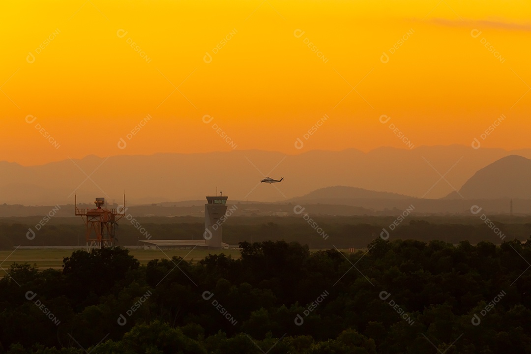 Lindo pôr do sol em com o aeroporto de Vitória em primeiro plano e um pouso de helicóptero ao fundo.