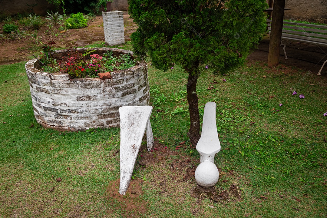 Esculturas em primeiro plano com um gramado e uma pequena árvore ao fundo.