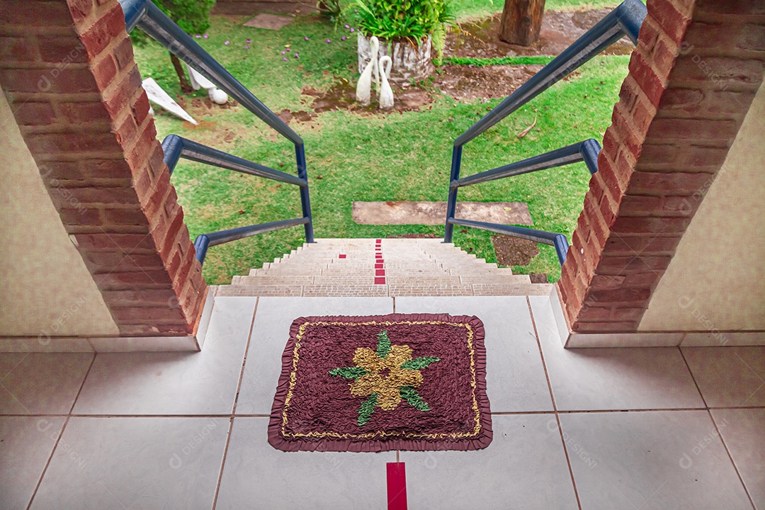 Escadaria com corrimão azul e ao fundo jardim com grama verde.
