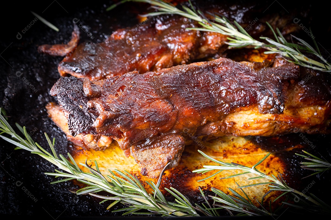 Costelinha de porco assada com molho barbecue de alecrim em uma tábua de madeira. Visão de perspectiva.