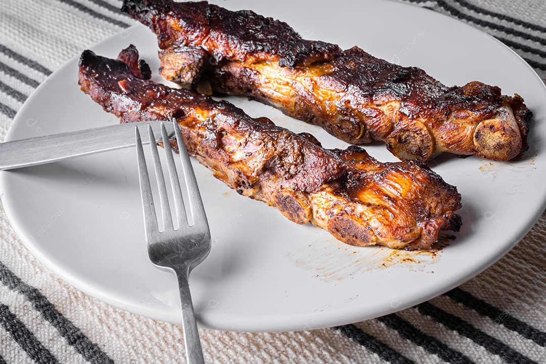 Costelinha de porco assada com molho barbecue de alecrim em uma tábua de madeira. Visão de perspectiva.