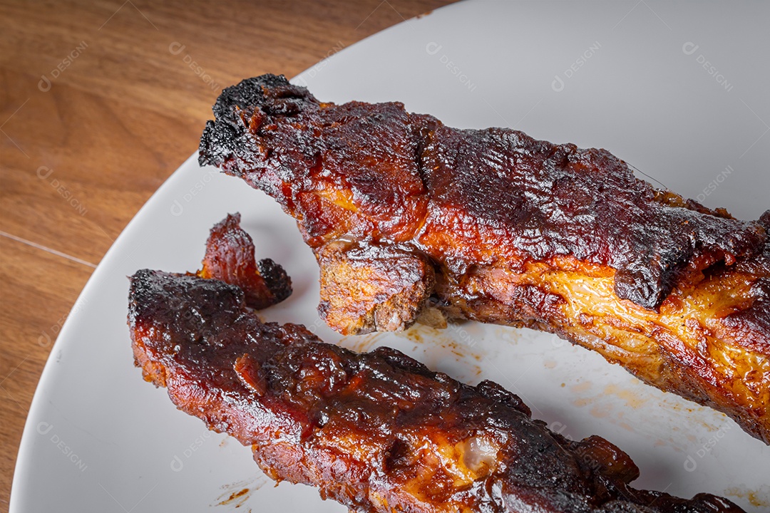 Costelinha de porco assada com molho barbecue de alecrim em uma tábua de madeira. Visão de perspectiva.