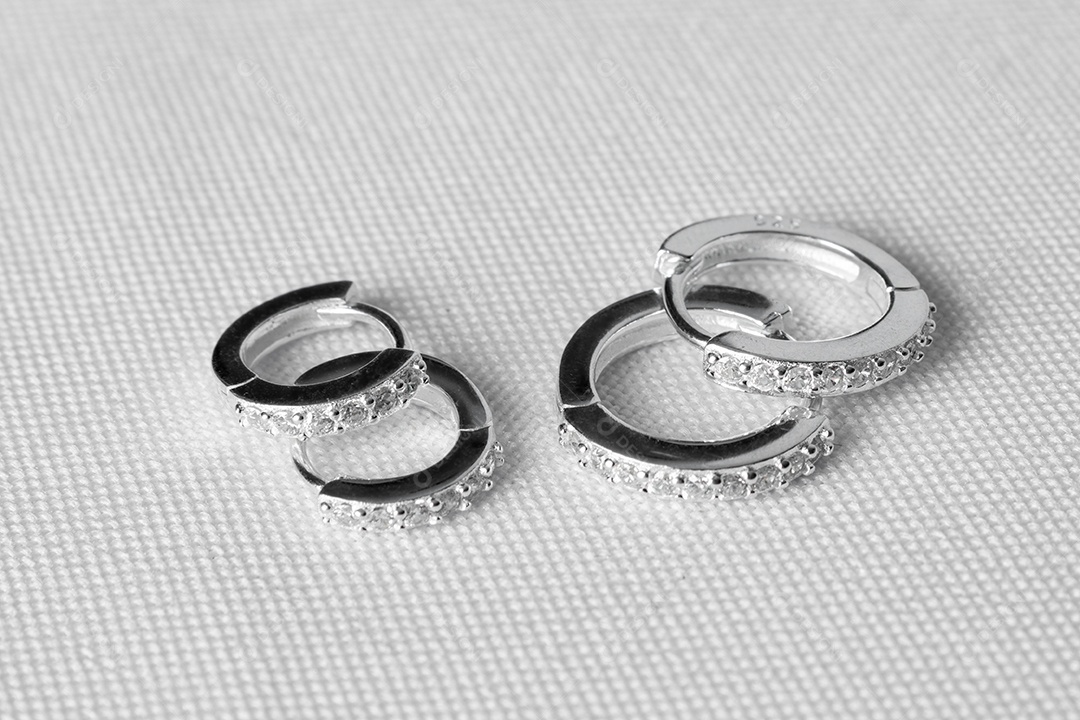 Joia brinco de prata elegante com pedras preciosas, sobre fundo branco. Dois pares.