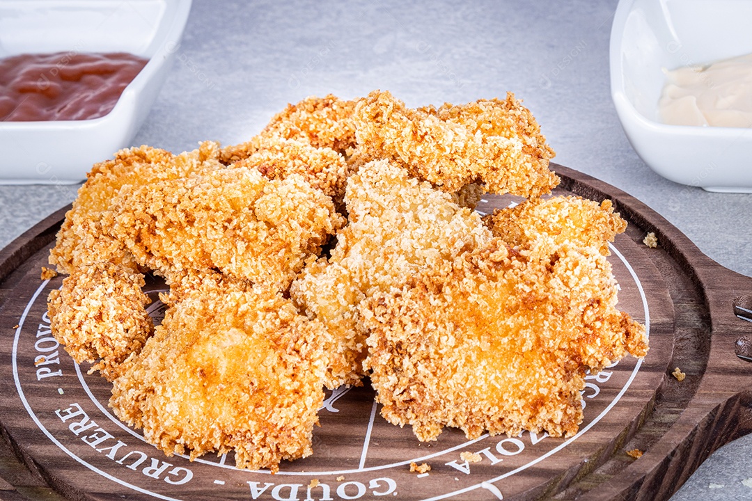 Delicioso Frango Frito em prato de porcelana branca com detalhe de arroz e coentro, além de molho de tomate e molho de maionese. Gráfico e faca ao lado do prato. Fundo marmorizado