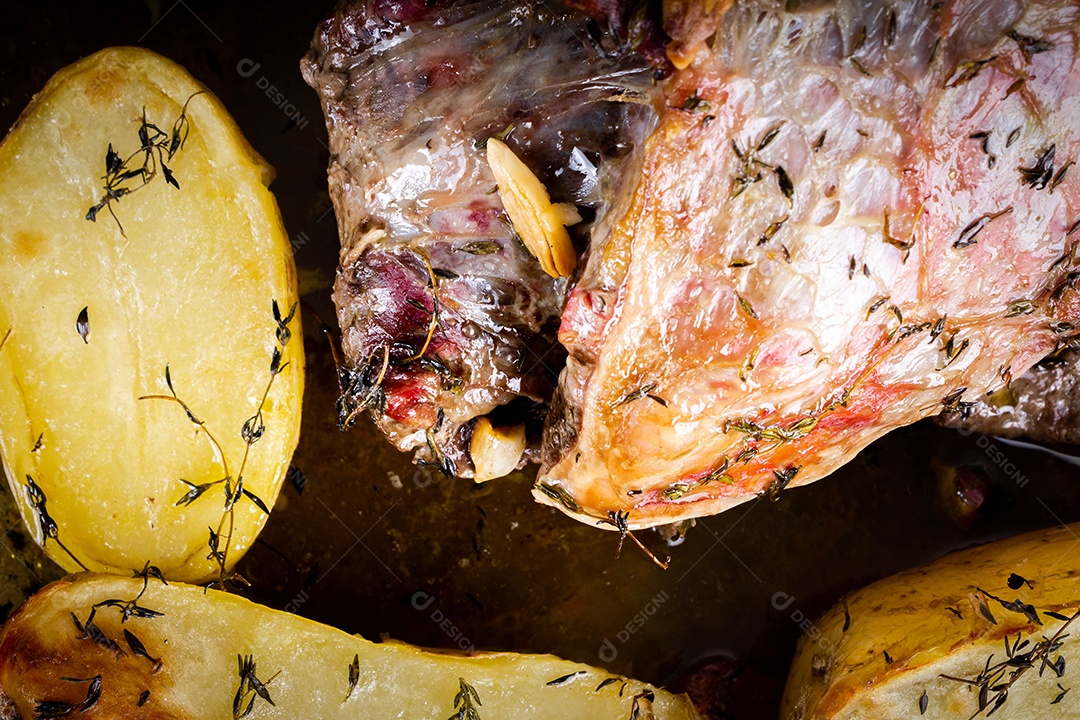 Carne para churrasco. Carne assada com batatas e tomilho numa tábua de madeira, totalmente cortada às rodelas. Vista do topo.