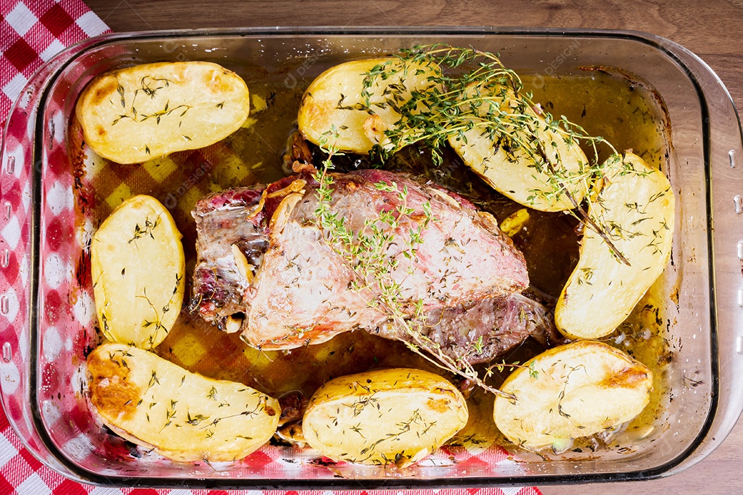 Carne para churrasco. Carne assada com batatas e tomilho numa tábua de madeira, totalmente cortada às rodelas. Vista do topo.