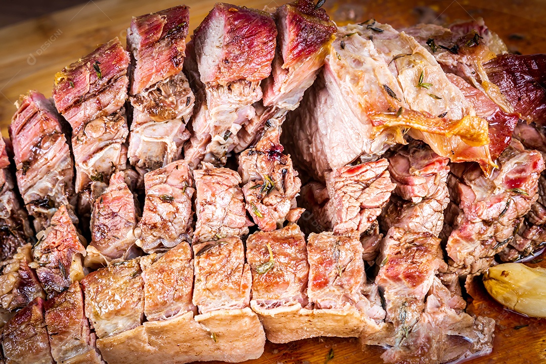 Carne para churrasco. Carne assada com batatas e tomilho numa tábua de madeira, totalmente cortada às rodelas. Vista do topo.