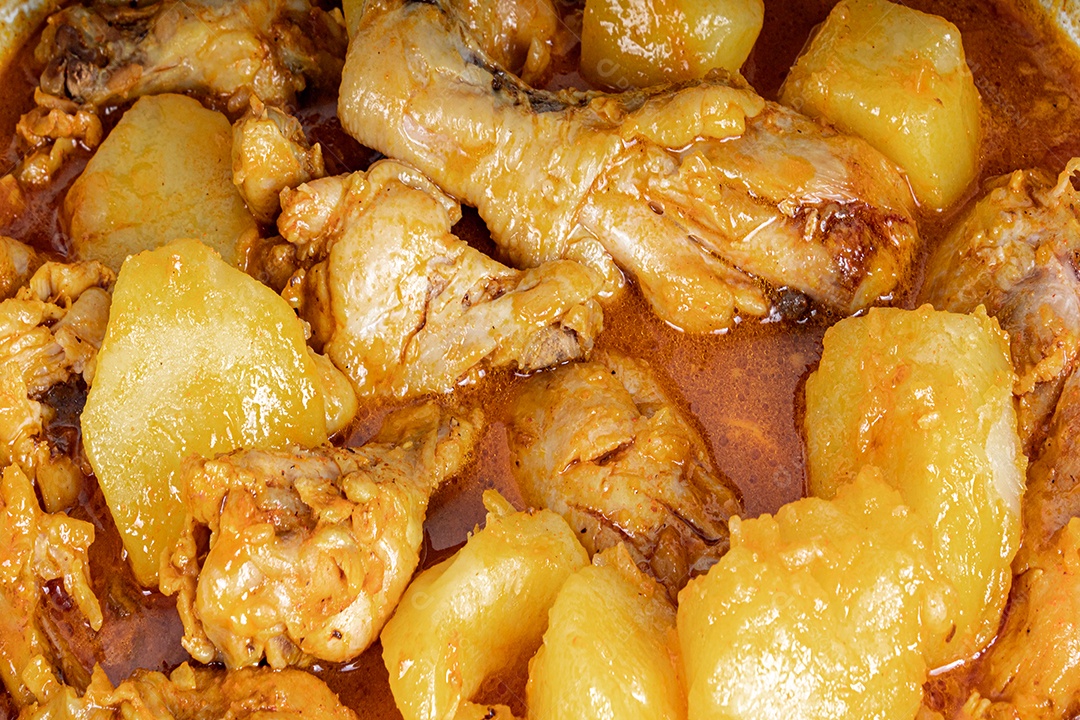 Ensopado de frango caseiro com tomate, cebola e batata na mesa de tecido preto e prato com arroz