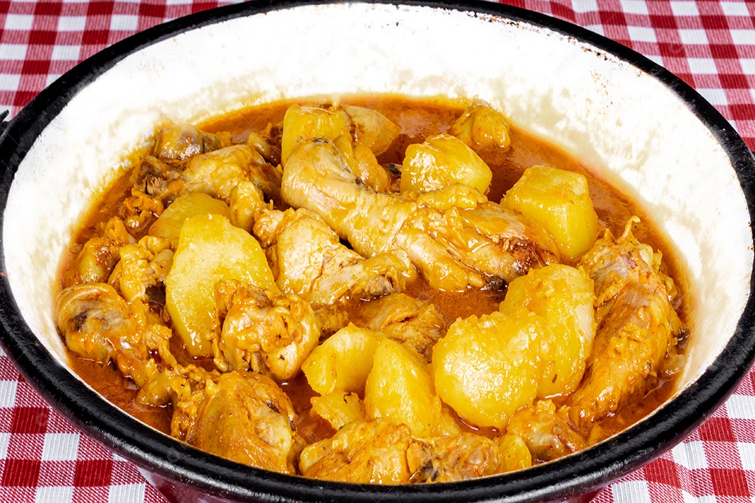 Ensopado de frango caseiro com tomate, cebola e batata na mesa de tecido preto e prato com arroz