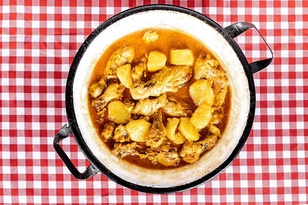 Ensopado de frango caseiro com tomate, cebola e batata na mesa de tecido preto e prato com arroz